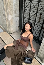'I am wearing a scoop-neck dark brown tank top with a very wide leather corset belt featuring detailed stitching and a big silver buckle. The belt is worn over the top and my matching brown flowing skirt. i also have black boots and am smiling at the came